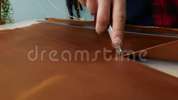 手工皮革工人用一把实用刀切去一块皮革关门视频的预览图