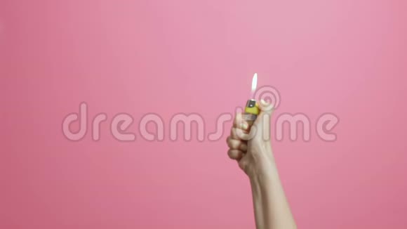女人的手打开打火机在粉红的彩色画室背景上闪烁扇子的轻创意的想法开始了视频的预览图