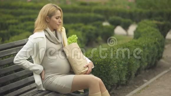金发美女躺在长椅上拿着购物袋怀孕困难视频的预览图