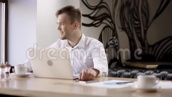 商人在等同事两个年轻人在咖啡馆里用笔记本电脑工作他们正在讨论和准备视频的预览图