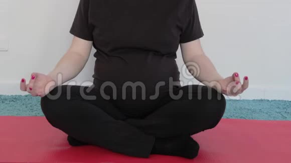 一个怀孕的女孩正在做瑜伽冥想肚子里的婴儿推着一个女人抚摸她的腹部视频的预览图