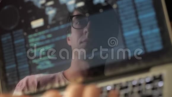 双曝光戴眼镜的人在笔记本电脑上工作程序员写蓝色代码在监视器中反射视频的预览图