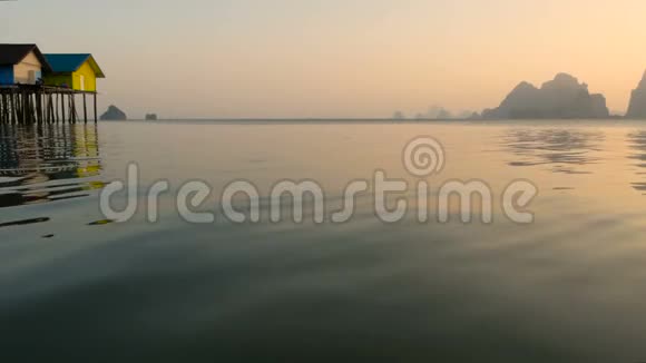 渔夫们房子在日落时从水边上方升起一艘船的剪影视频的预览图
