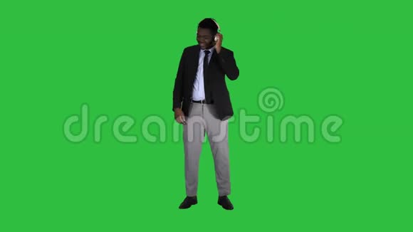 黑色商人用绿色屏幕上的耳机和音乐跳舞色度键视频的预览图