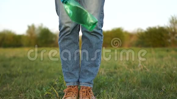 一个男人在草地上扔一个绿色塑料瓶的特写镜头地球社会的塑料污染视频的预览图