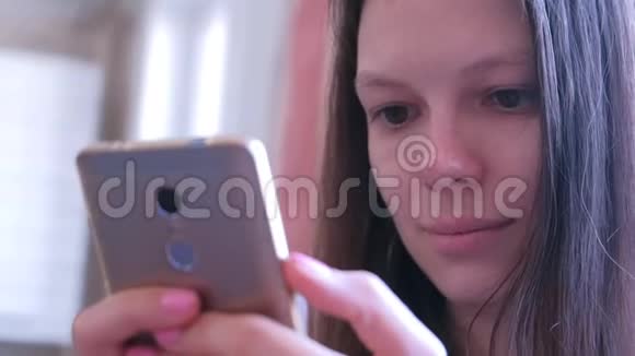 肖像年轻女子在智能手机上阅读书籍在线浏览互联网页面视频的预览图