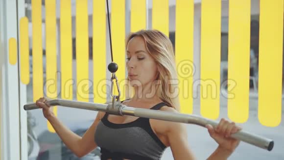 有魅力的年轻白种人女孩在运动中穿着与健身器材在职业健身房锻炼视频的预览图