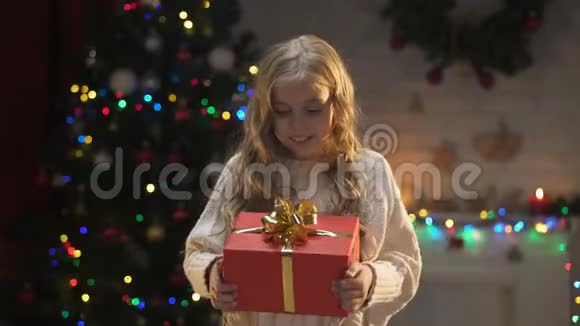 可爱的小女孩拥抱圣诞礼物靠近闪闪发光的装饰品梦想视频的预览图
