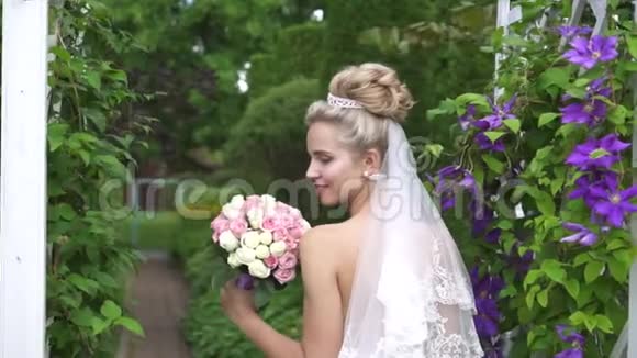 美丽的形象新娘在美丽的花园里捧着一束鲜花视频的预览图