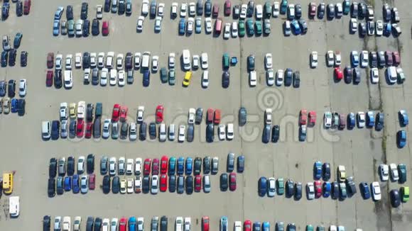 在停车场或销售汽车经销商市场上的许多汽车的高空俯视空中飞行视频的预览图