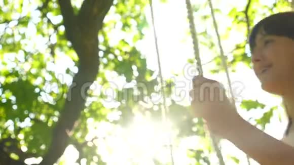女孩在阳光下在橡树下荡秋千动作缓慢特写视频的预览图