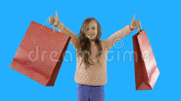 一个七岁的卷发小女孩看着镜头微笑着挥舞着新买的东西或礼物视频的预览图