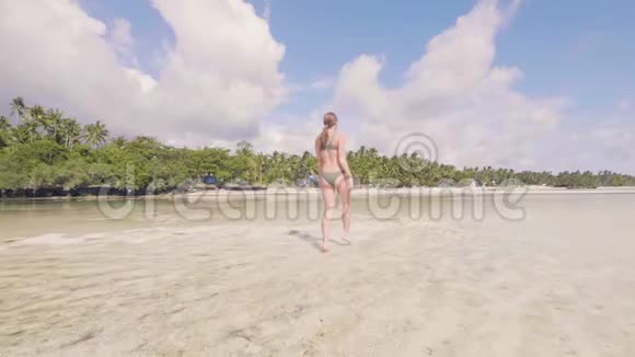 年轻女子穿着比基尼在天堂度假胜地沙滩上的海水上散步低角度视角美丽的女人在奔跑视频的预览图