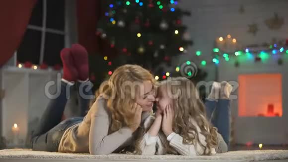 年轻的女人和女孩在圣诞树下抚摸微笑着对着镜头节日视频的预览图