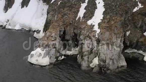 海岸上有一个洞穴的岩石被雪覆盖视频的预览图