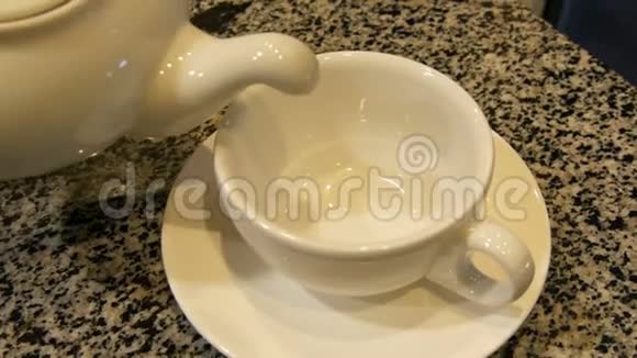 白瓷茶壶里的茶倒在杯子里视频的预览图