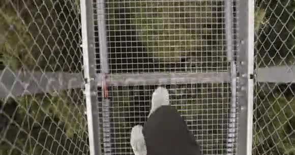 在山上的一座金属吊桥上行走的男腿特写视频的预览图