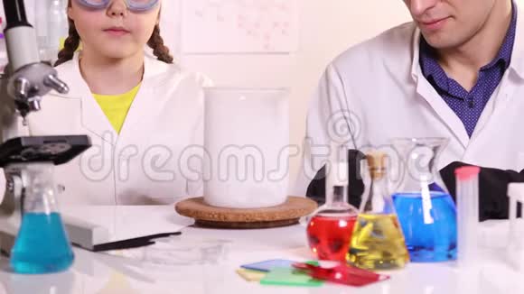 一位年轻的科学家为一名女学生上化学课视频的预览图