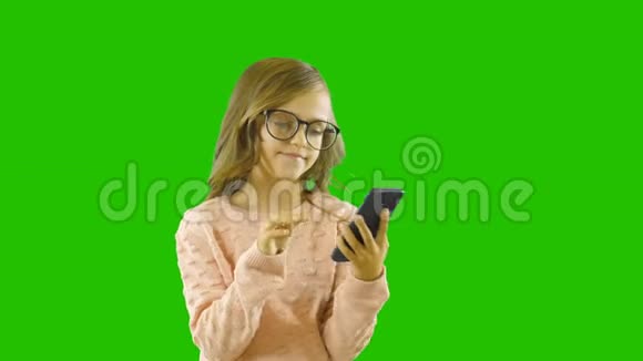 可爱的小女孩正在积极地在电话里找东西发现和微笑在孤立的背景上拍摄视频的预览图