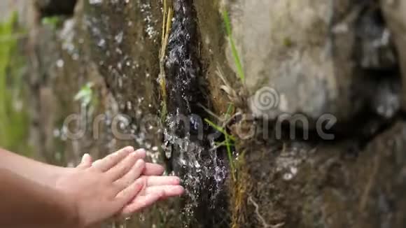 特写幼儿手一个孩子在一条清澈透明的溪水中洗了手河水顺流而下视频的预览图