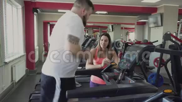 他在健身中心的跑步机上跑步减肥训练从私人教练为胖子健康和健身房演习视频的预览图