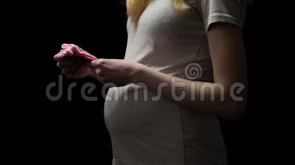 孕妇把粉红色的婴儿袜子放在肚子上等着小女孩孩子视频的预览图