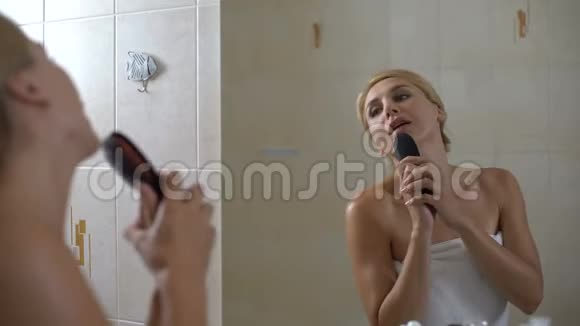 女人用发刷唱歌假装是流行歌星在浴室里玩视频的预览图