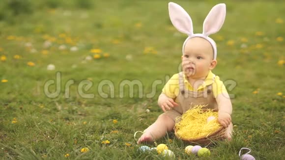 宝贝首先看到复活节彩蛋他握着他的手从坐在公园草地上的幸福中呼喊快乐视频的预览图