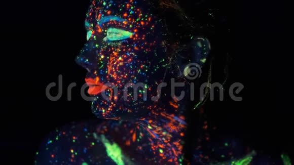 油漆在紫外线下发光一个女孩的肖像用发光的油漆着色视频的预览图