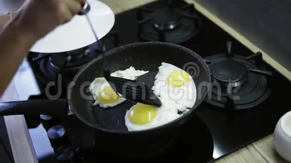 一个女人手把热锅里的煎蛋放在白色盘子里家晚早餐近景视频的预览图