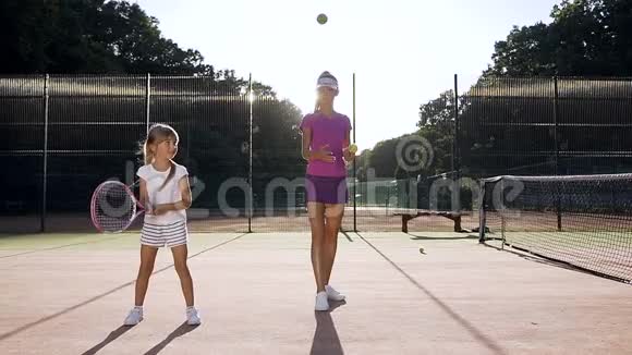 在球场上和教练一起训练时小女孩的击球动作很柔和视频的预览图