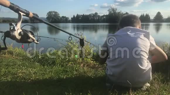 在湖边钓鱼的男孩美丽的鱼塘巴丁附近班斯卡比斯特里察斯洛伐克捕鱼的地方阳光照耀着鱼塘视频的预览图