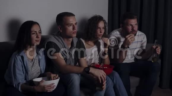四个朋友一起吃爆米花喝啤酒一起看恐怖电影非常着迷和害怕坐着不动视频的预览图