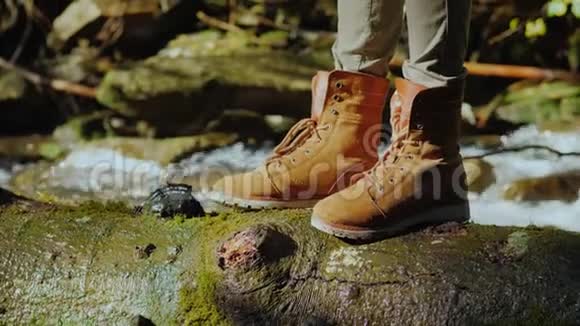 旅行者的脚站在一条山溪旁的湿木头上旅游和徒步旅行概念视频的预览图