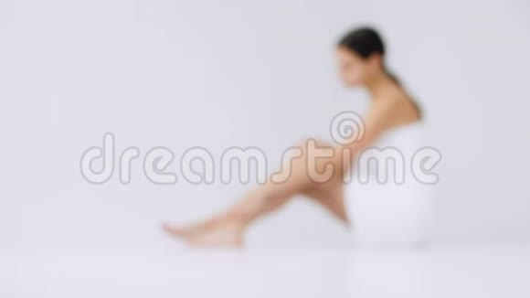 背景模糊美丽的白种人年轻女士用清爽的奶油抚摸她的腿视频的预览图