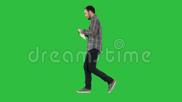 自信认真的人在绿色屏幕上的平板电脑上行走和工作Chroma键视频的预览图