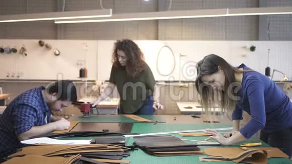 三个皮革工人在工作室制作袋子细节视频的预览图