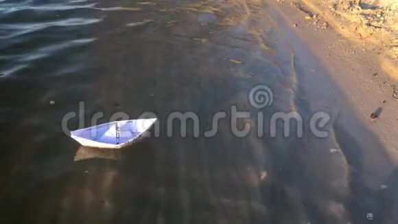 一艘用纸做的小船在海滩附近的波浪上摆动视频的预览图