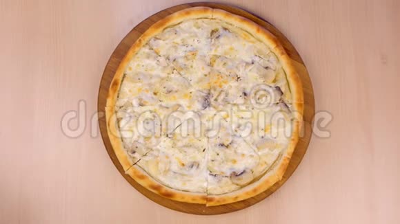 用蘑菇切比萨饼和奶酪在桌子上的木板上切片特写俯视图视频的预览图