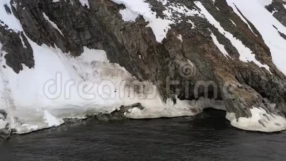 海岸上有一个洞穴的岩石被雪覆盖视频的预览图
