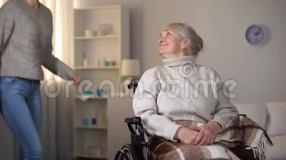 孙女拥抱轮椅上微笑的老妇人家人的爱和关怀视频的预览图