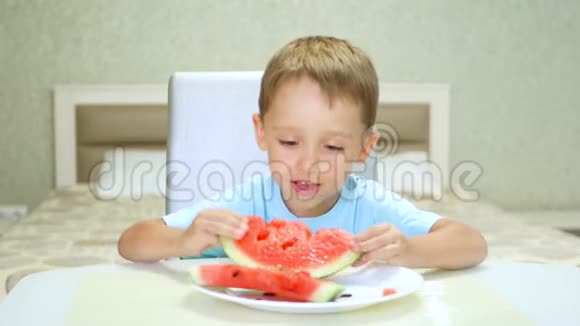 快乐的孩子坐在桌子旁高兴地吃西瓜视频的预览图