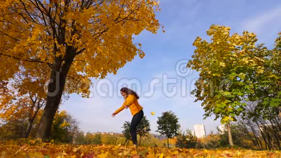 女人拿着吐在空中明亮的黄色落叶视频的预览图