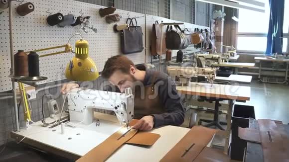 英俊的工人在机器上缝制人造皮带的肖像视频的预览图