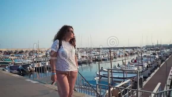 快乐的成年女人在阳光明媚的早晨欣赏城市码头的景色独自散步视频的预览图