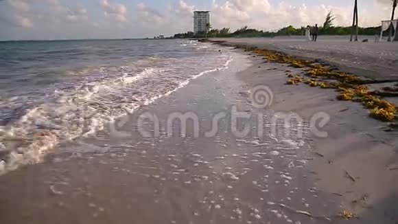 日落时分一对年轻夫妇在墨西哥布兰卡岛拍摄了一张热带海滩的低POV照片视频的预览图