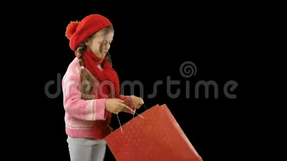 一个十岁左右的女孩戴着一顶红色针织帽子和一条带辫子的围巾手里拿着一个包裹她打开了眼睛视频的预览图