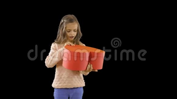 一个小女孩手里拿着一个心脏形状的红色盒子她的喜悦打开了它微笑着快乐着视频的预览图