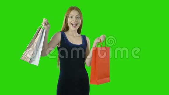 红发快乐女孩在孤立的绿色背景下购物后带着纸袋的肖像视频的预览图