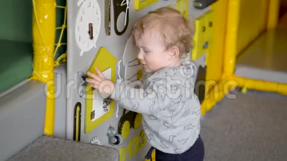可爱的小男孩在墙上玩忙碌的木板教育玩具儿童专用餐视频的预览图